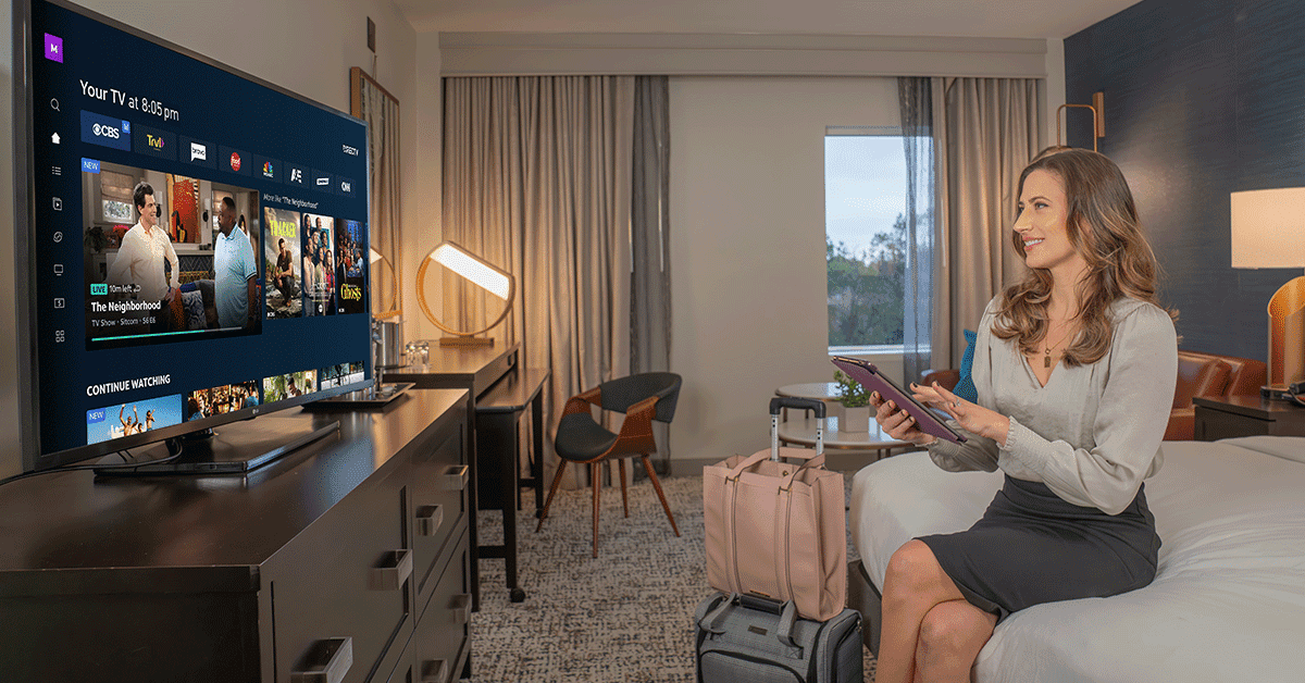 Hotel guest relaxing in a room with DIRECTV on the wall-mounted television